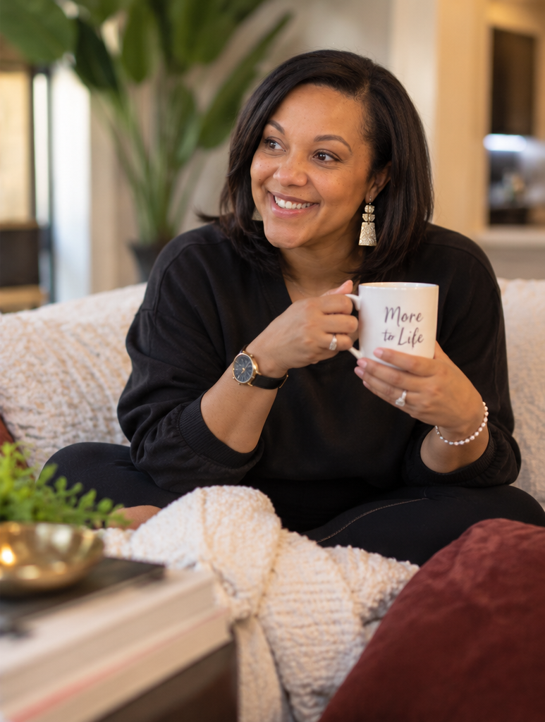 Kristen Moore seated on a cream sofa, holding a mug that reads More to Life